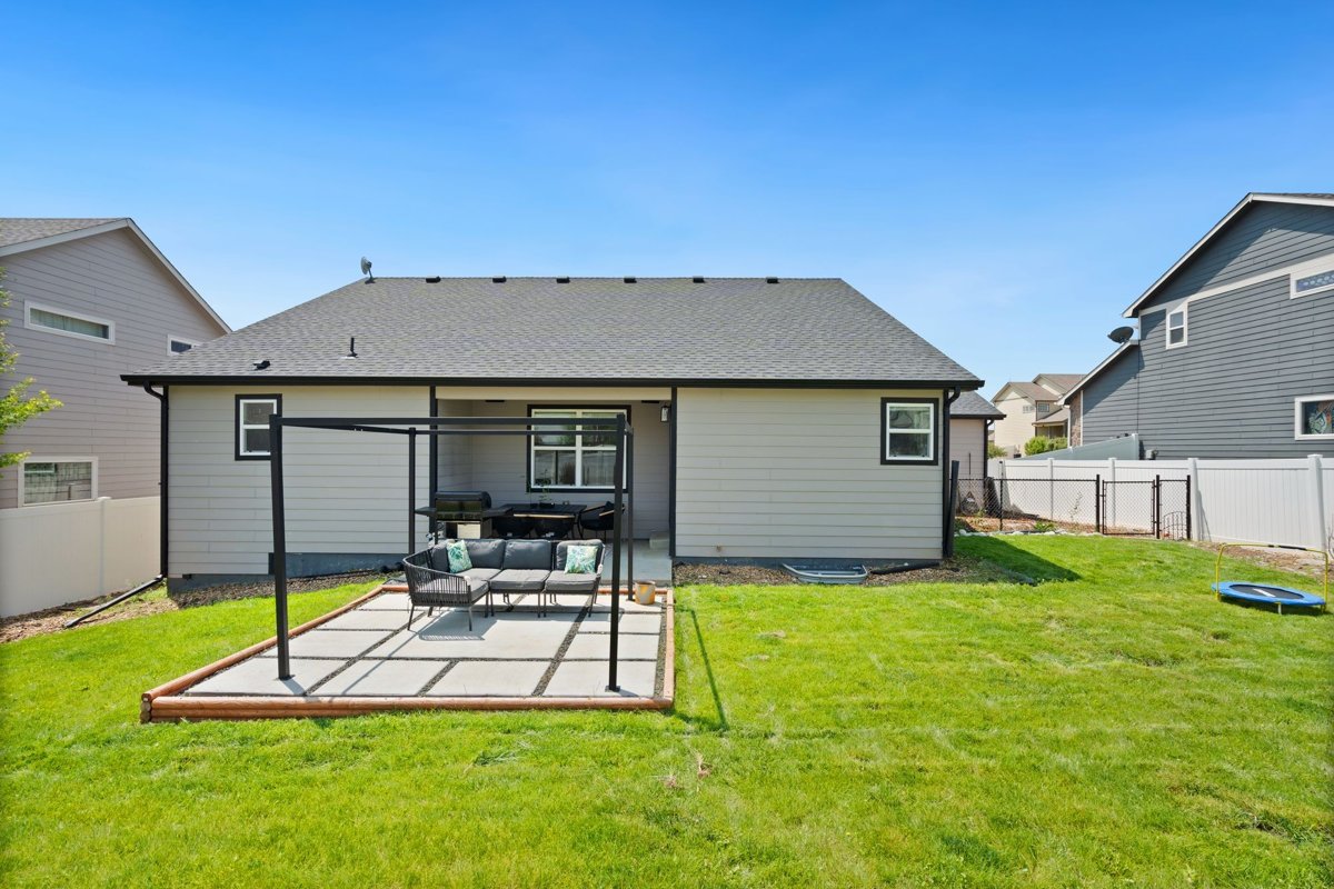 Completed paved backyard seating area surrounded by a green lawn and privacy fencing